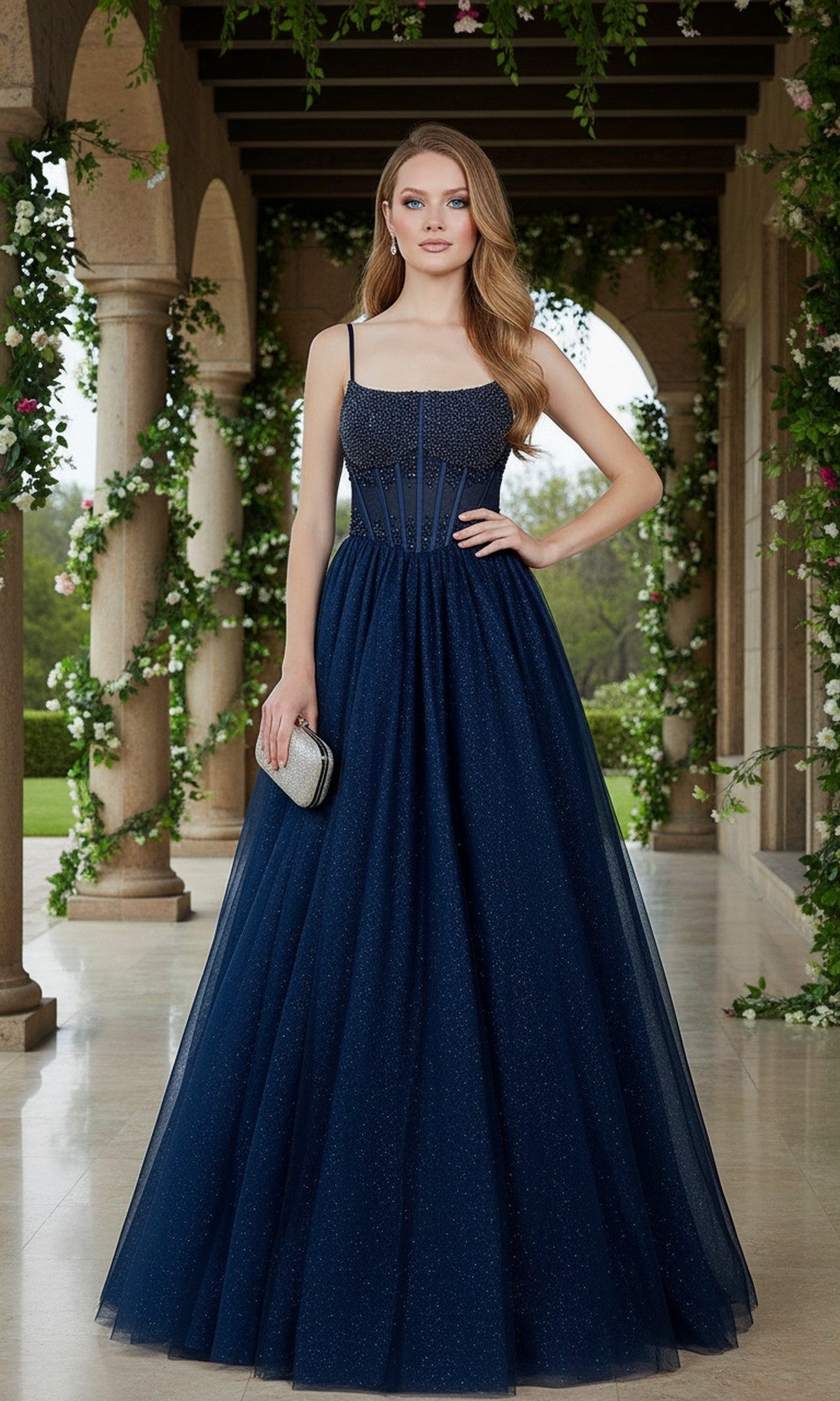 A woman in the Cinderella Couture 8459J long navy prom dress with a beaded corset bodice stands on a garden walkway, surrounded by stone columns and lush greenery.